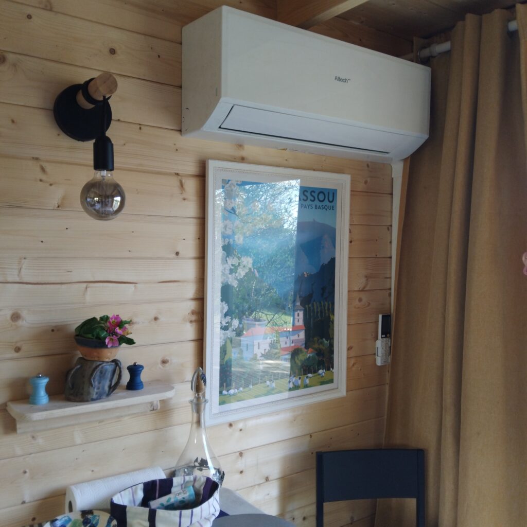 Climatiseur Altech sur mur en bois avec affiche Pays Basque et lampe style industriel dans un intérieur chaleureux.
