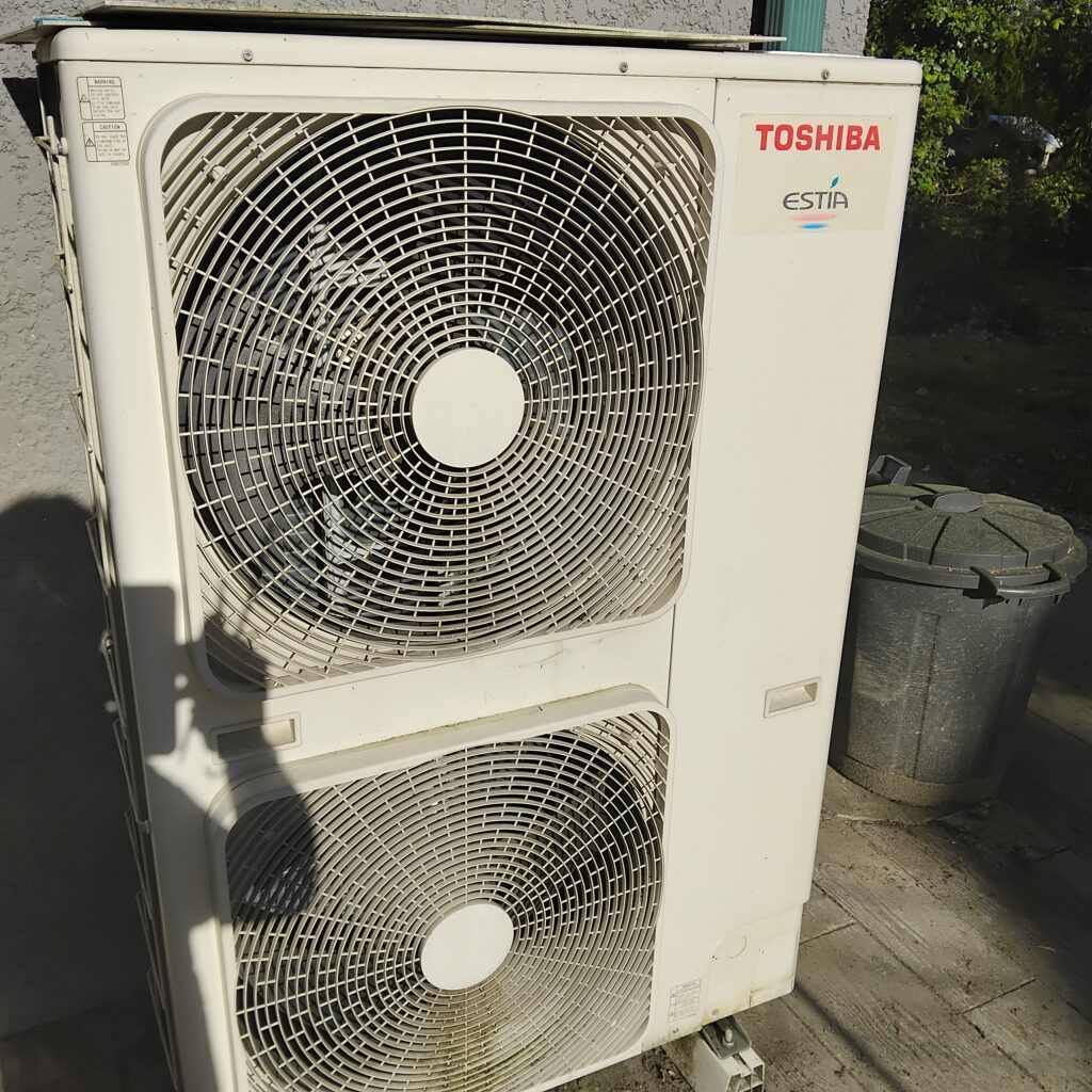 Pompe à chaleur Toshiba Estia : Unité extérieure performante Unité extérieure de pompe à chaleur Toshiba Estia blanche avec deux grands ventilateurs circulaires.