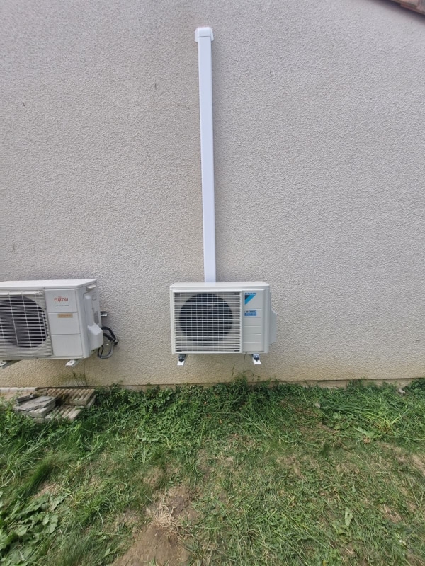 Installation d'unités de climatisation Fujitsu et Daikin Unités extérieures de climatisation Fujitsu et Daikin installées sur un mur beige avec goulotte de protection blanche.