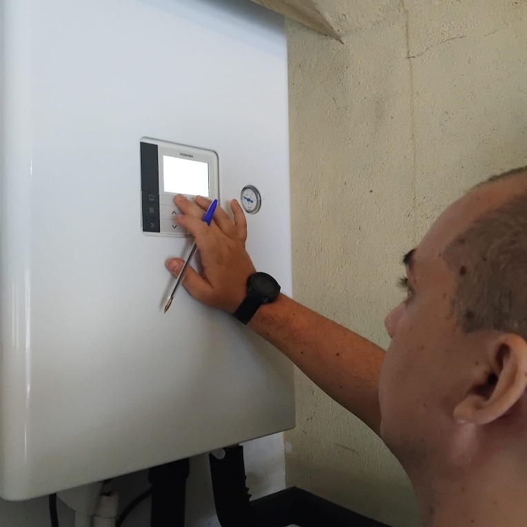 Entretien Pompe à Chaleur Toshiba : Réglage de l'Interface Technicien réglant l'interface Toshiba d'un système de chauffage mural.